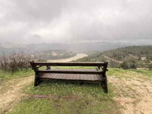 תצפית בהרי ירושלים על מאגר בית זית והסכר, נוף ירוק ומים זורמים ביום חורפי